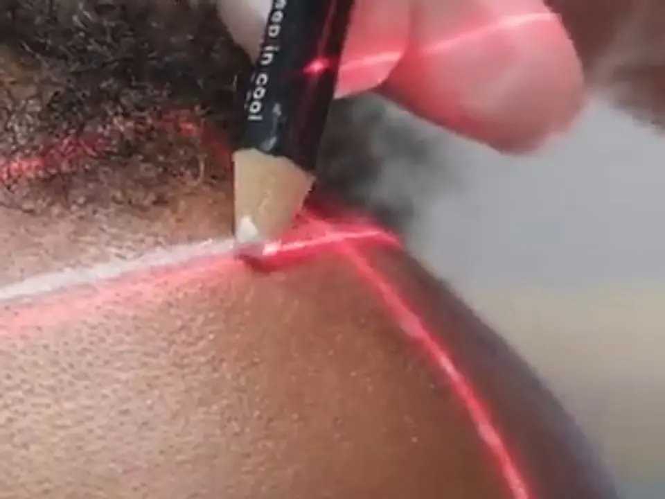 Un’attaccatura tracciata con una guida laser e una matita su capelli afro